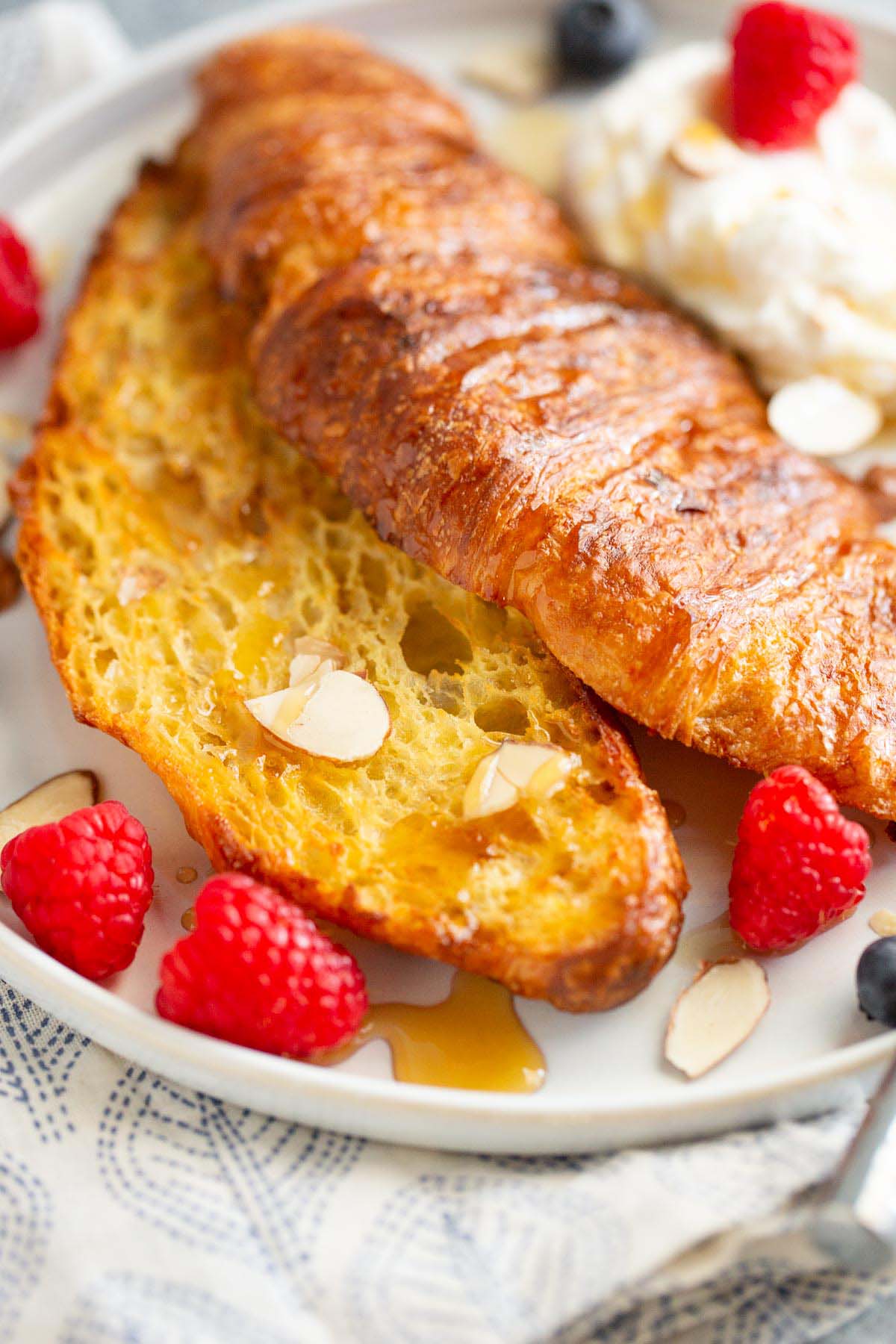 Croissant french toast topped with berries and whipped cream.