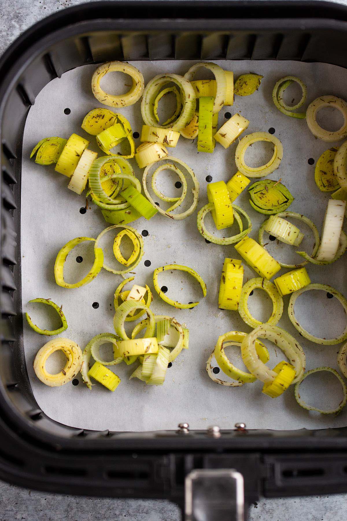 Uncooked leeks in air fryer basket.