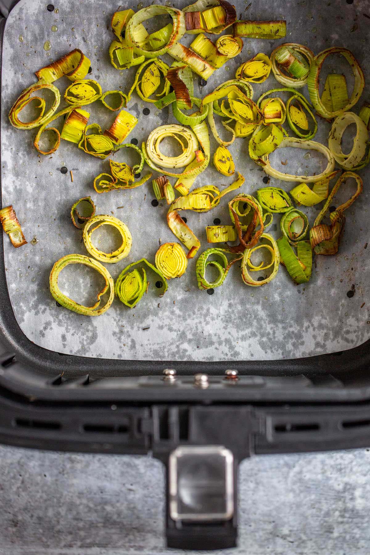 Cooked leeks in air fryer basket.