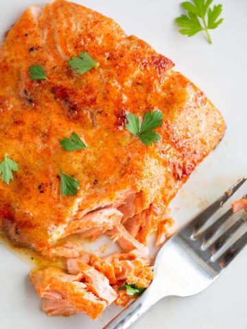 Maple dijon salmon on a plate with fresh parsley.