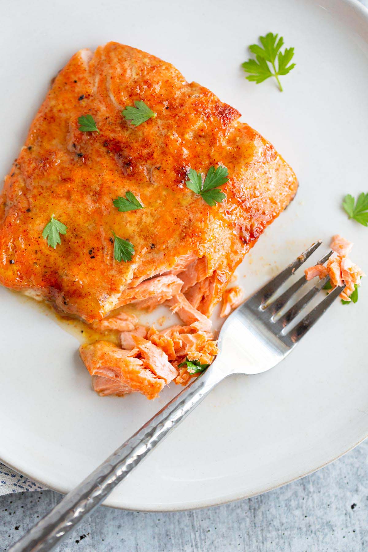 Flaked air fryer maple dijon salmon on a plate with a fork.