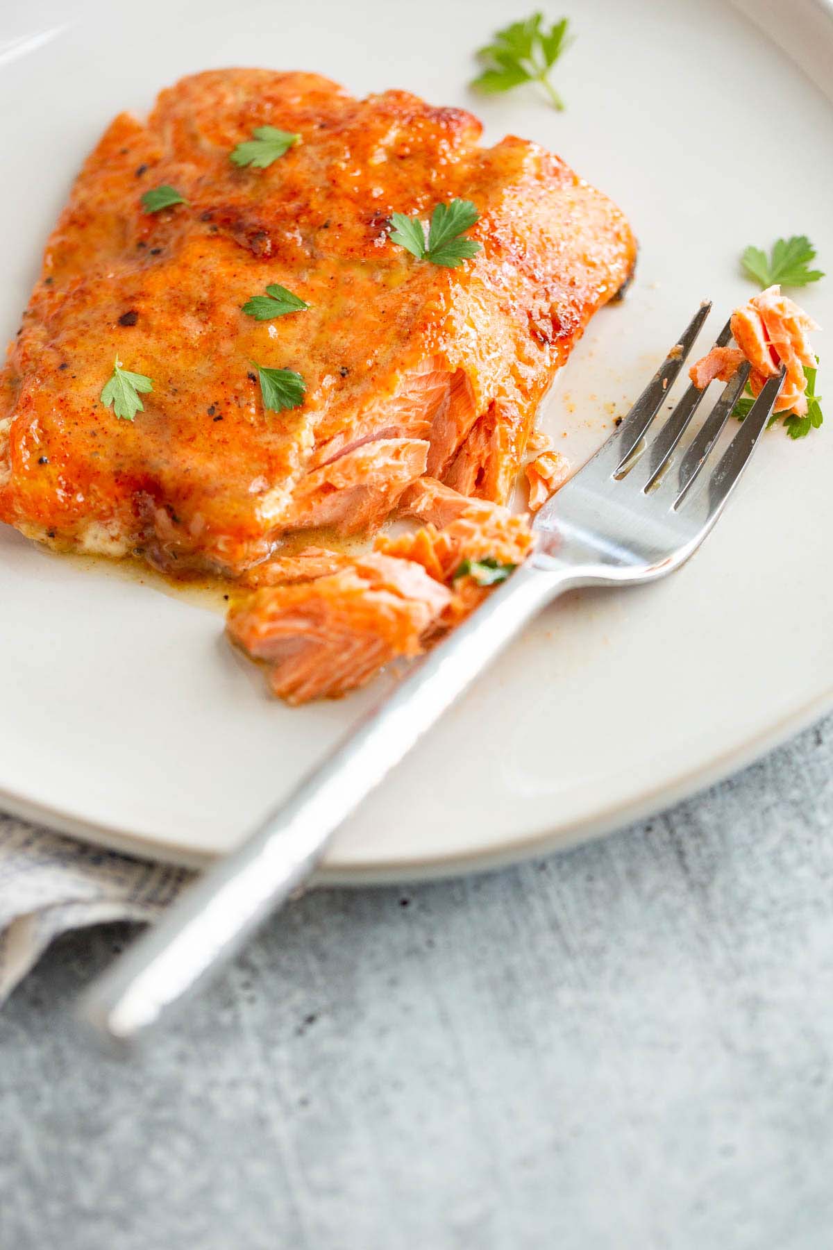 Flaked air fryer maple dijon salmon on a plate with a fork.