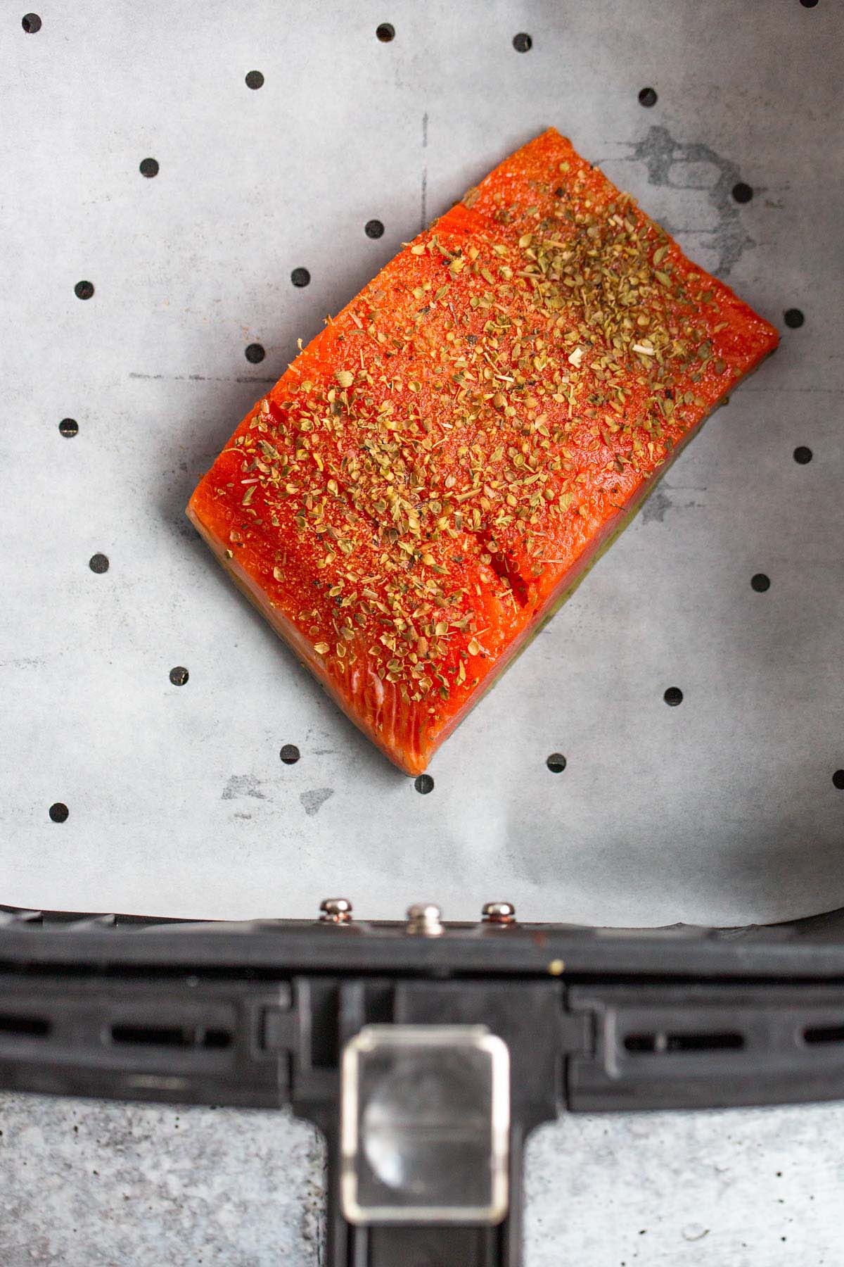 Uncooked salmon in air fryer basket.