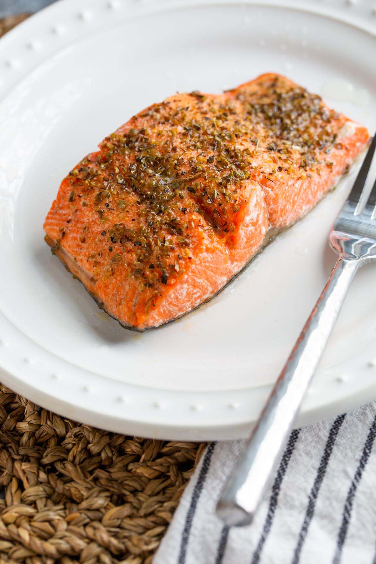 Cooked salmon on a plate up close with a fork.