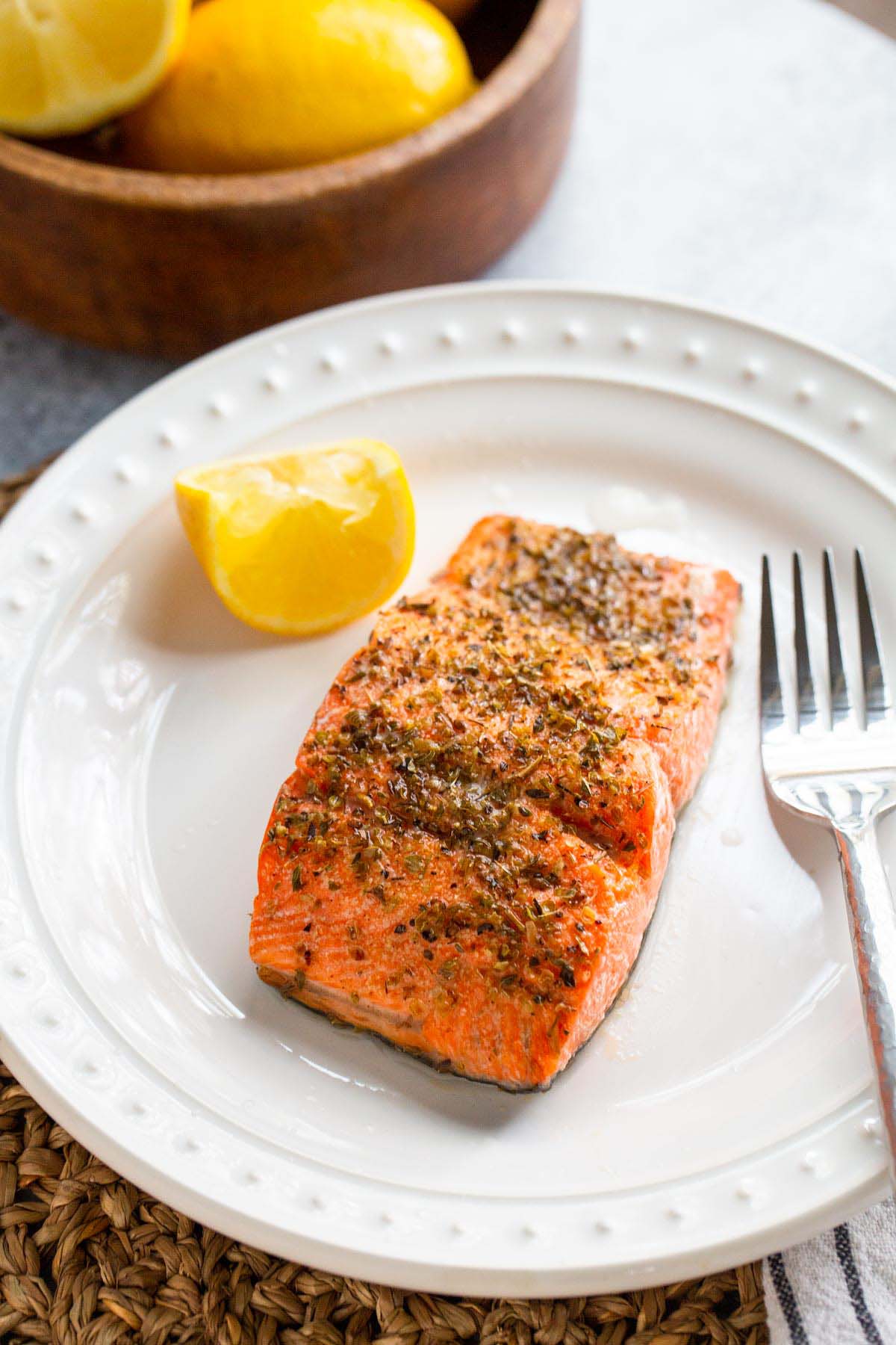 Cooked salmon on a plate with lemon wedge.