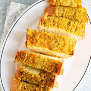 Air fryer pesto garlic bread sliced on a plate.