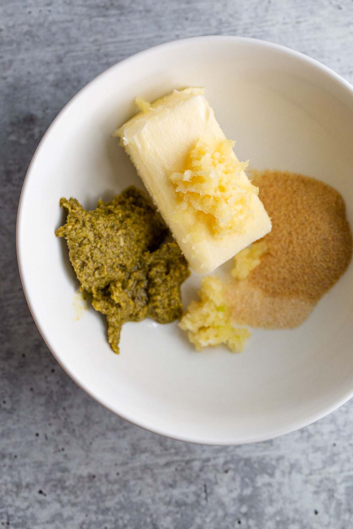 Butter, pesto, and seasonings in a bowl.