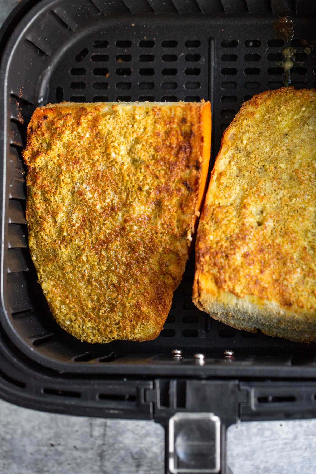 Pesto garlic bread in air fryer basket.