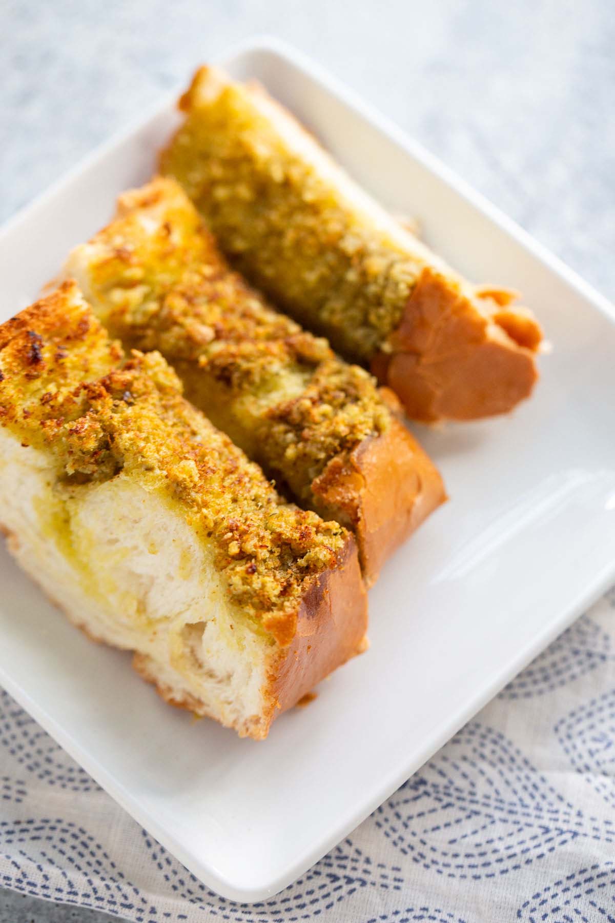 Three pieces of pesto garlic bread on a plate.