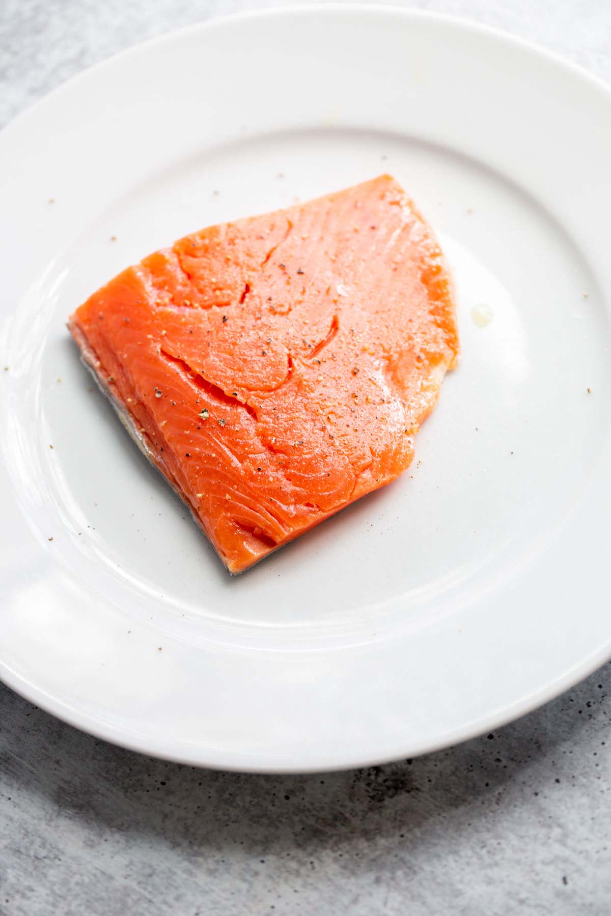 Uncooked salmon on white plate.