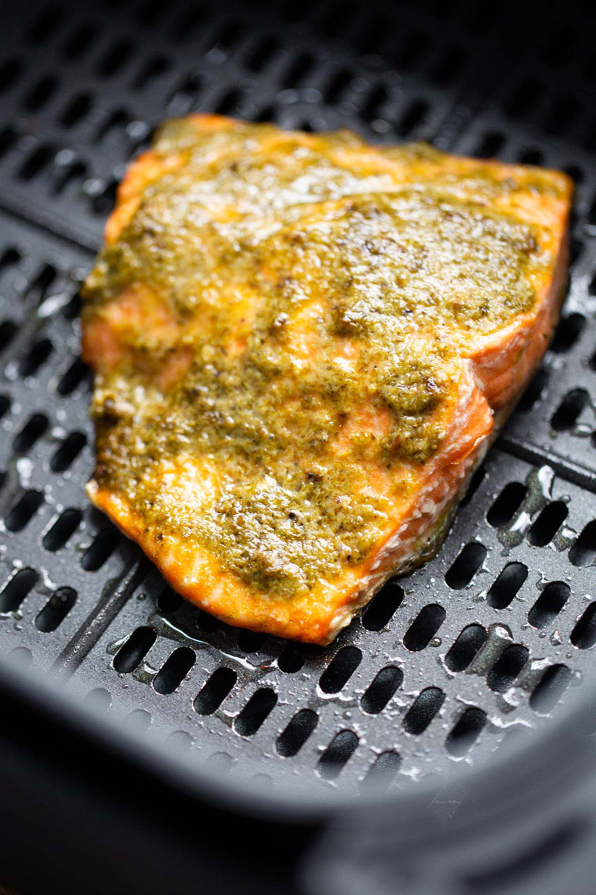 Cooked salmon in air fryer basket.