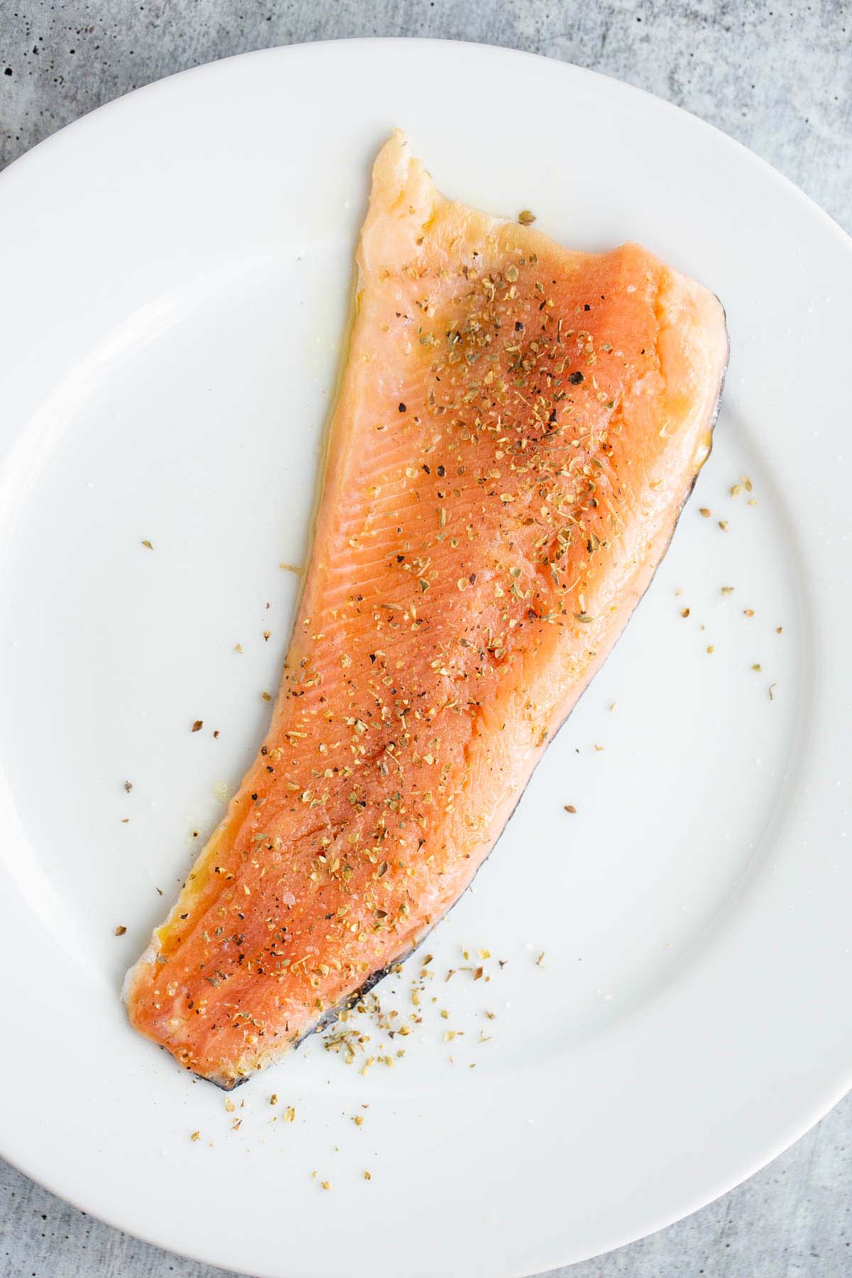 Uncooked rainbow trout fillet on a plate.