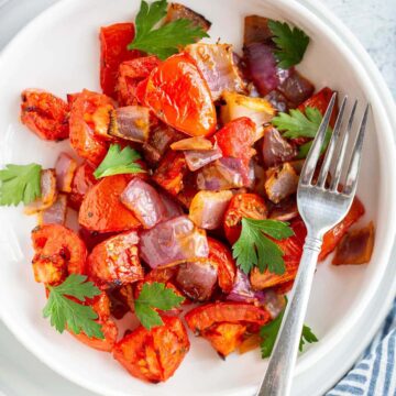 Air fried tomatoes and onions in a bowl with fresh parsley.