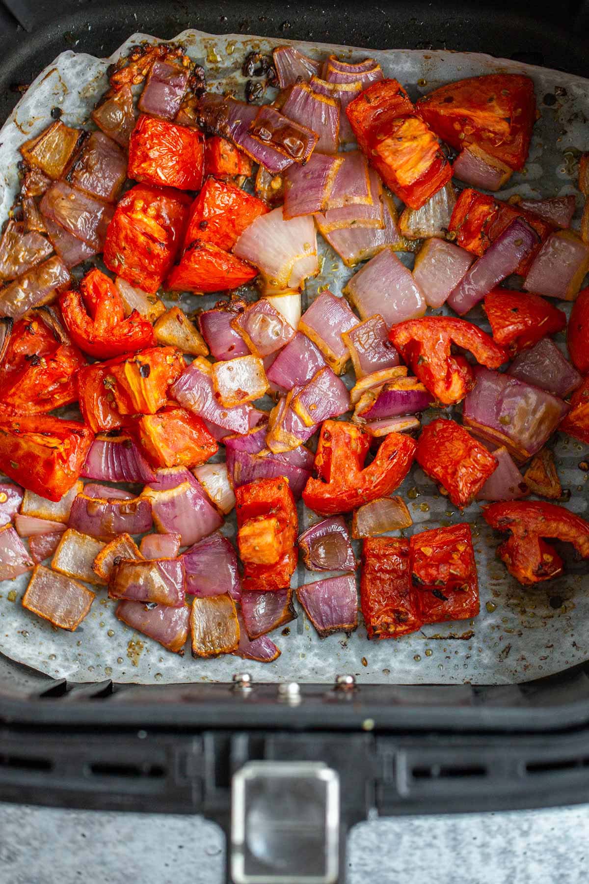 Air fried tomatoes and onions in air fryer basket.