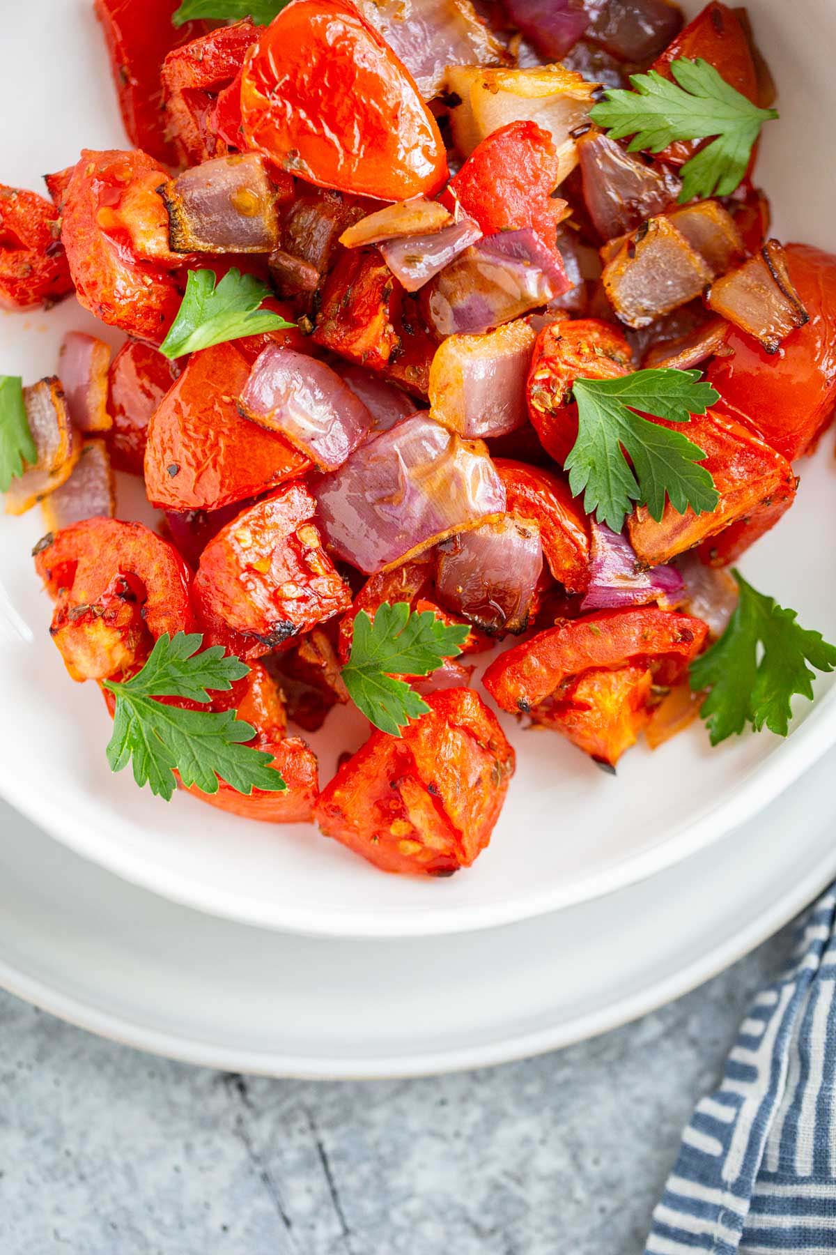 Air fried tomatoes and onions in a bowl with fresh herbs.