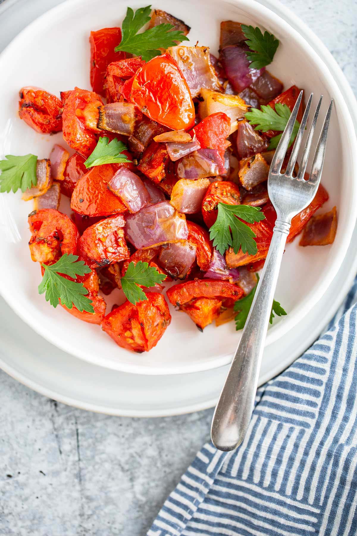 Air fried tomatoes and onions in a bowl with fresh herbs.