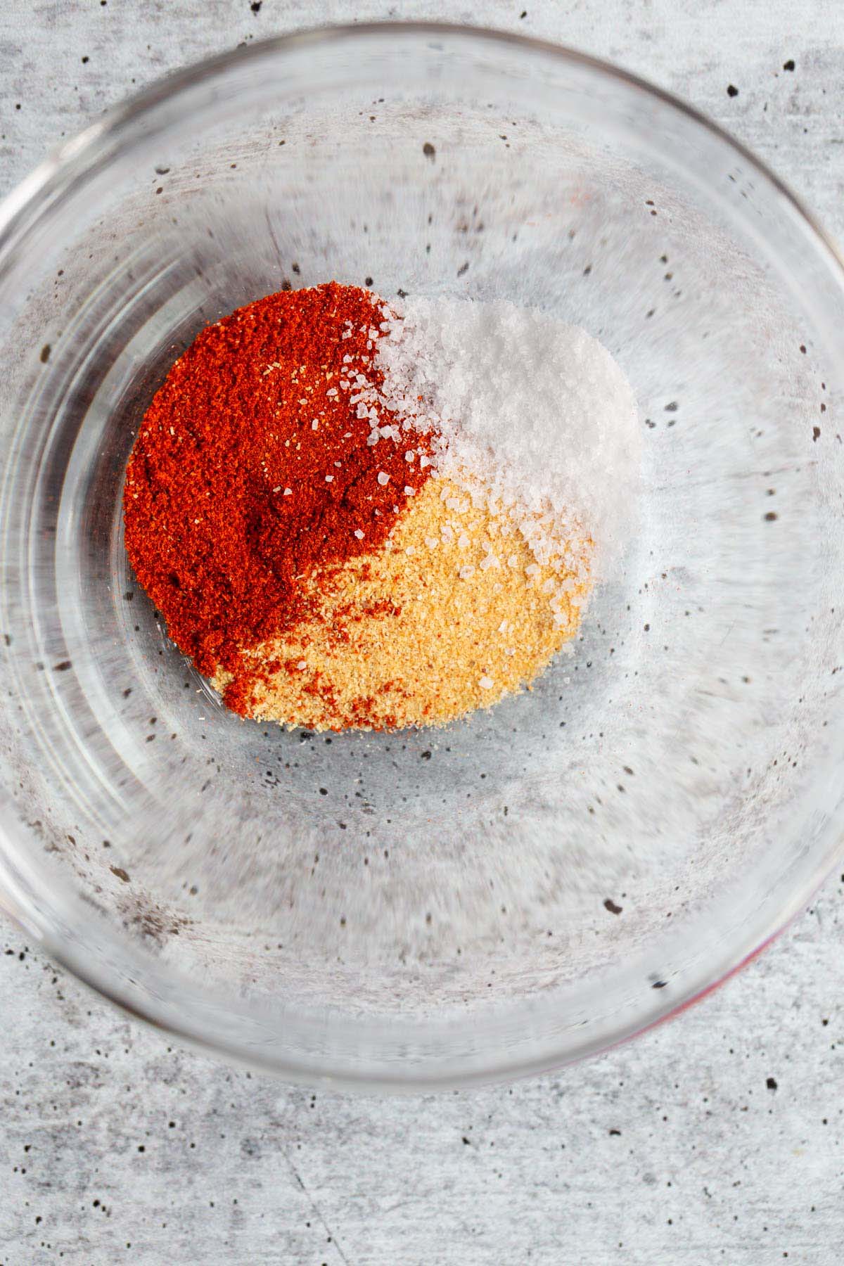 Smoked paprika, garlic powder, and salt in a glass bowl.