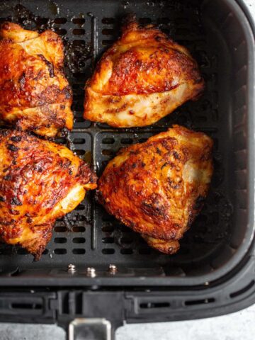 Peri peri chicken thighs in air fryer basket.