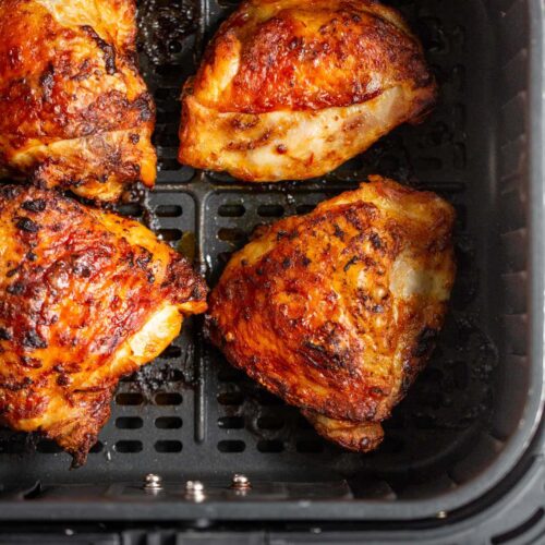 Peri peri chicken thighs in air fryer basket.