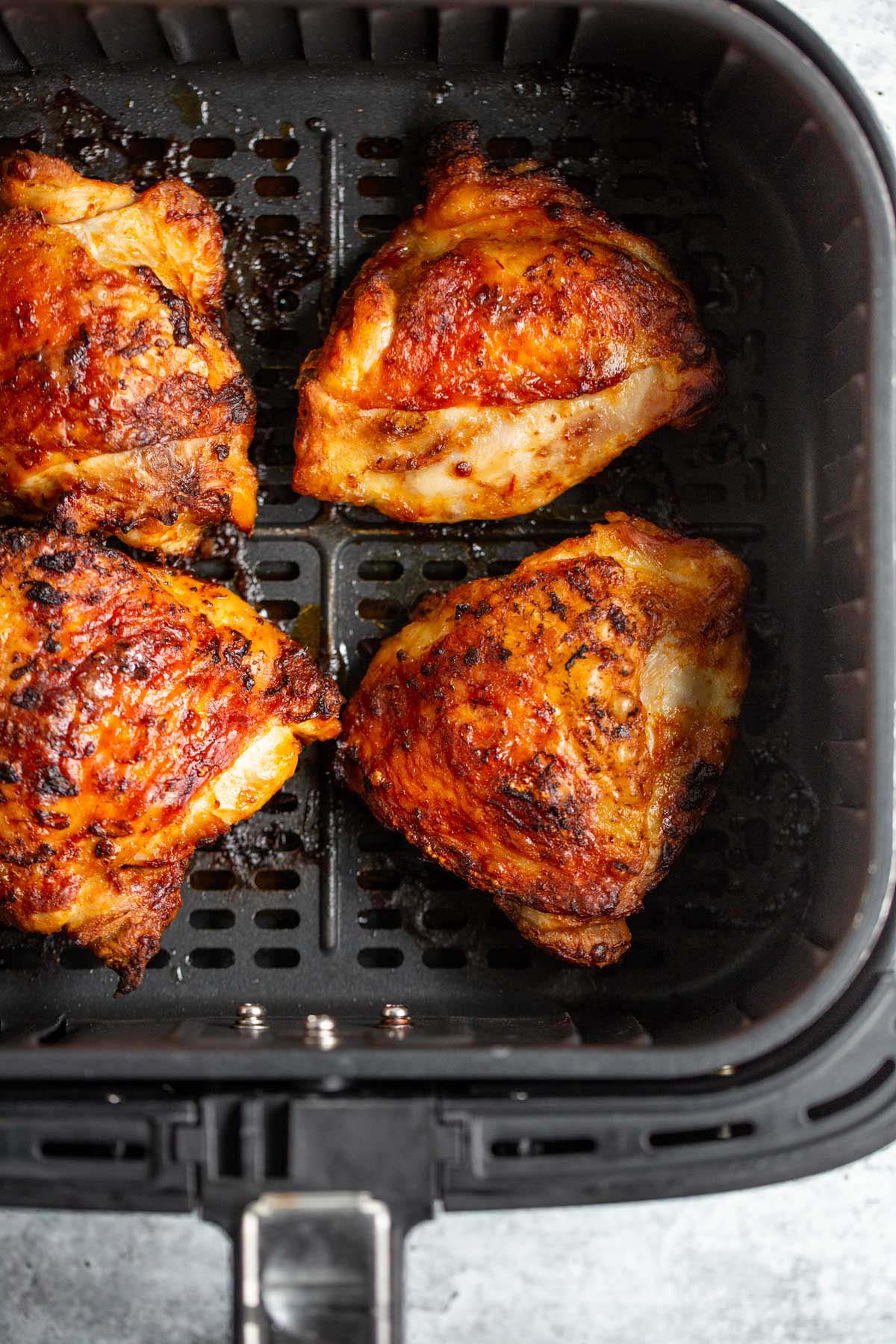 Peri peri chicken thighs in air fryer basket.