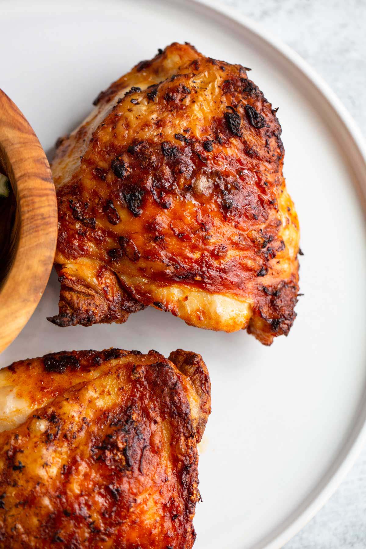 Peri peri chicken thighs on a white plate.