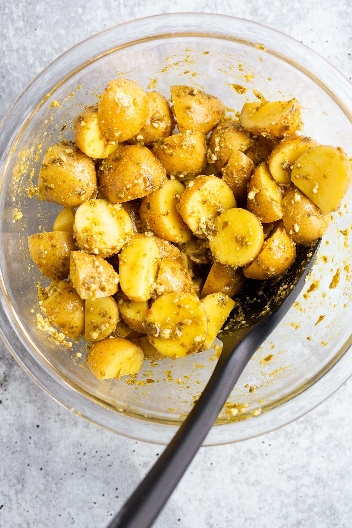 Potatoes tossed with pesto in a bowl.