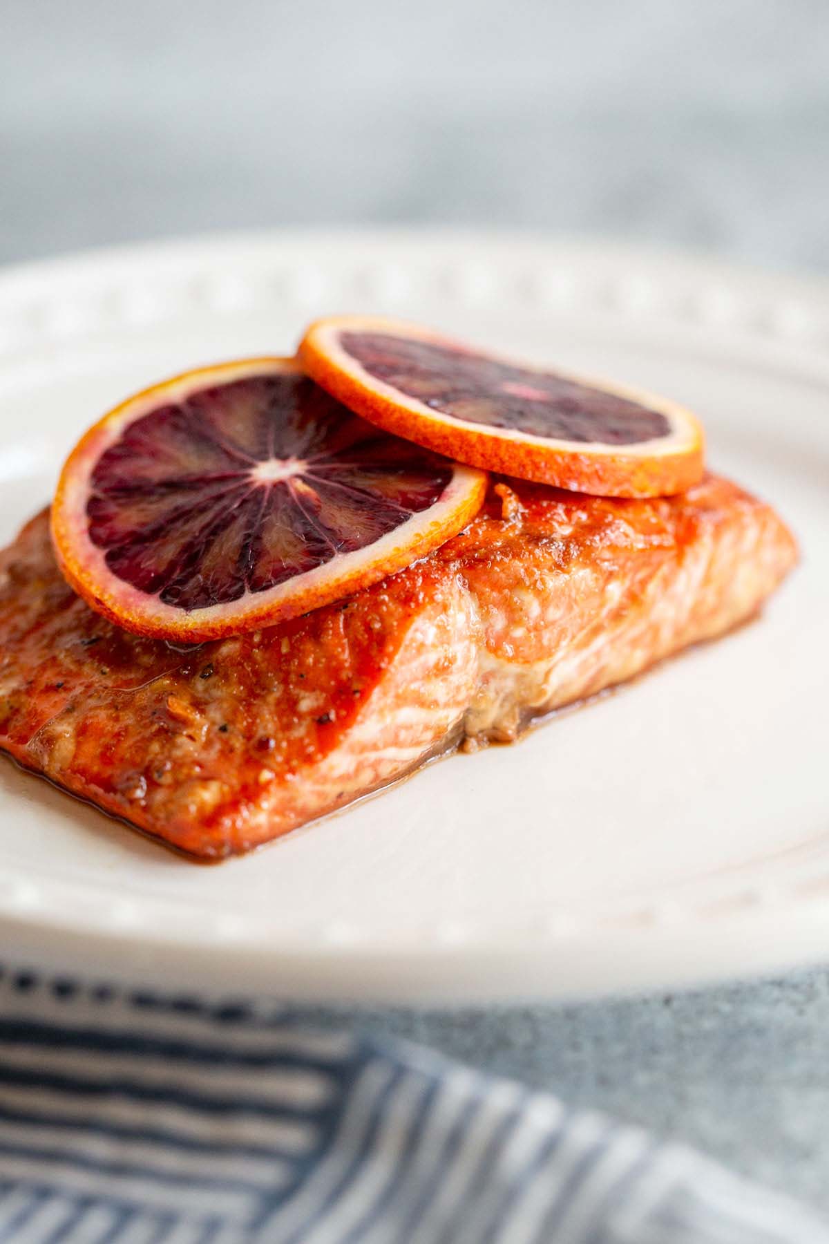 Salmon on a white plate with blood orange slices.