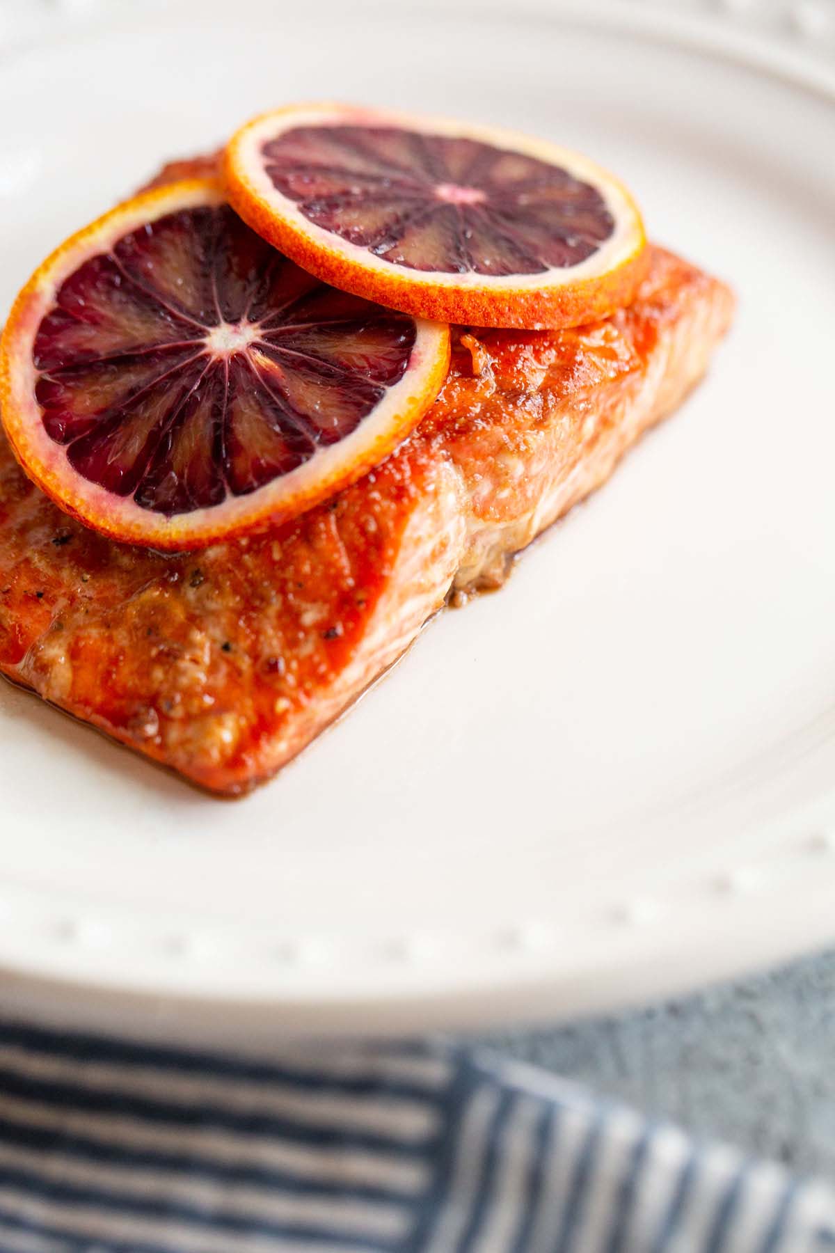 Salmon on a white plate with blood orange slices.