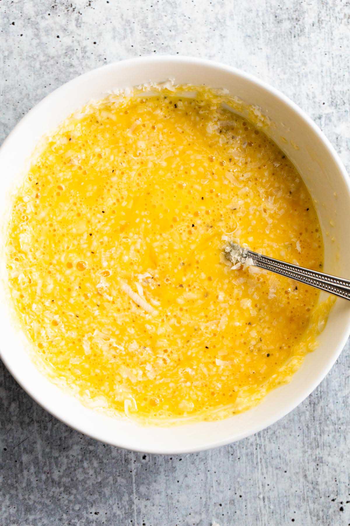 Eggs, pepper, and cheese mixed together in a bowl.