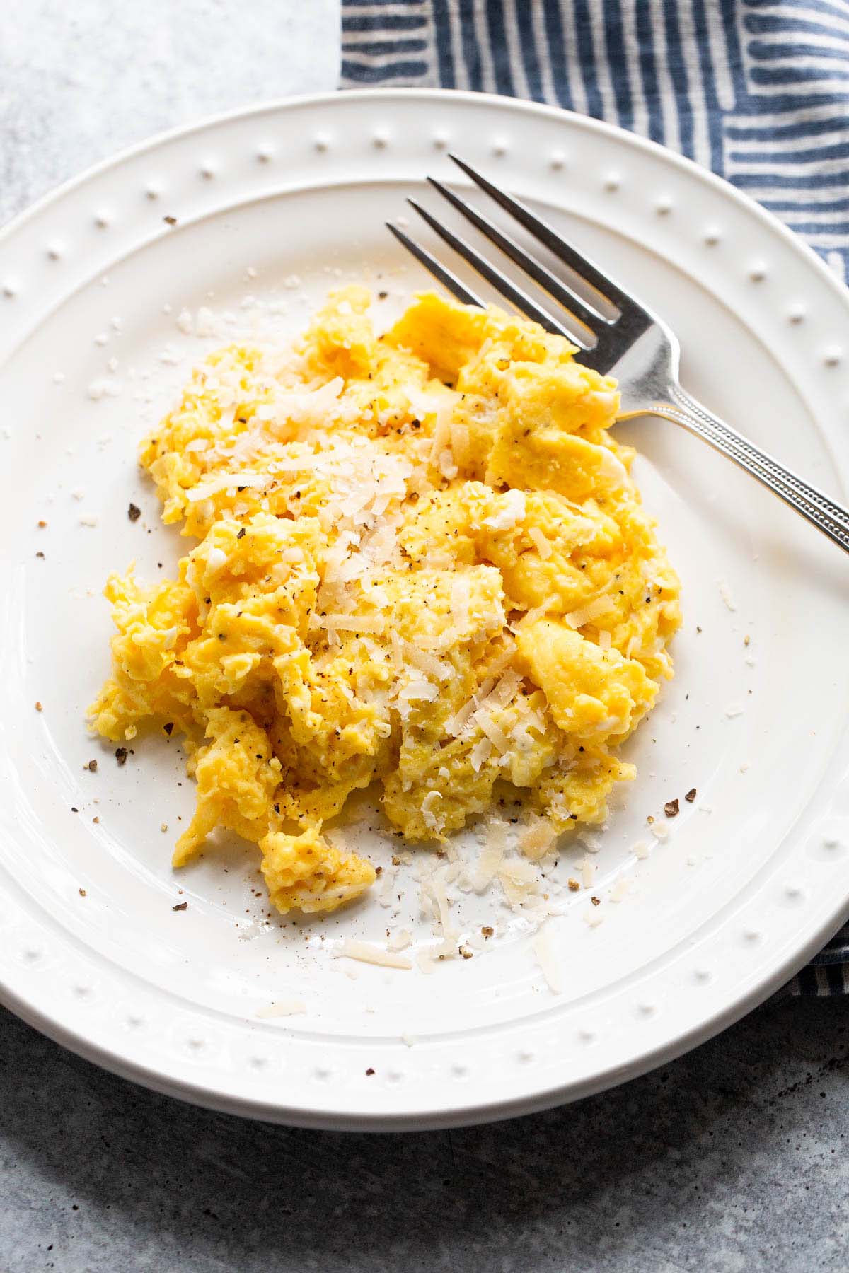 Cacio e pepe scrambled eggs on a white plate.