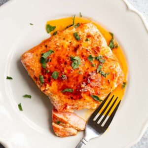 Peri Peri Salmon on a white plate with parsley on top.