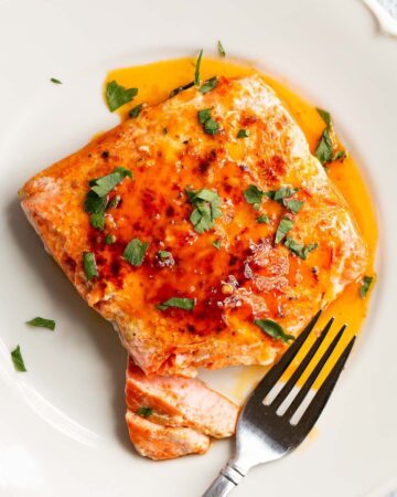 Peri Peri Salmon on a white plate with parsley on top.