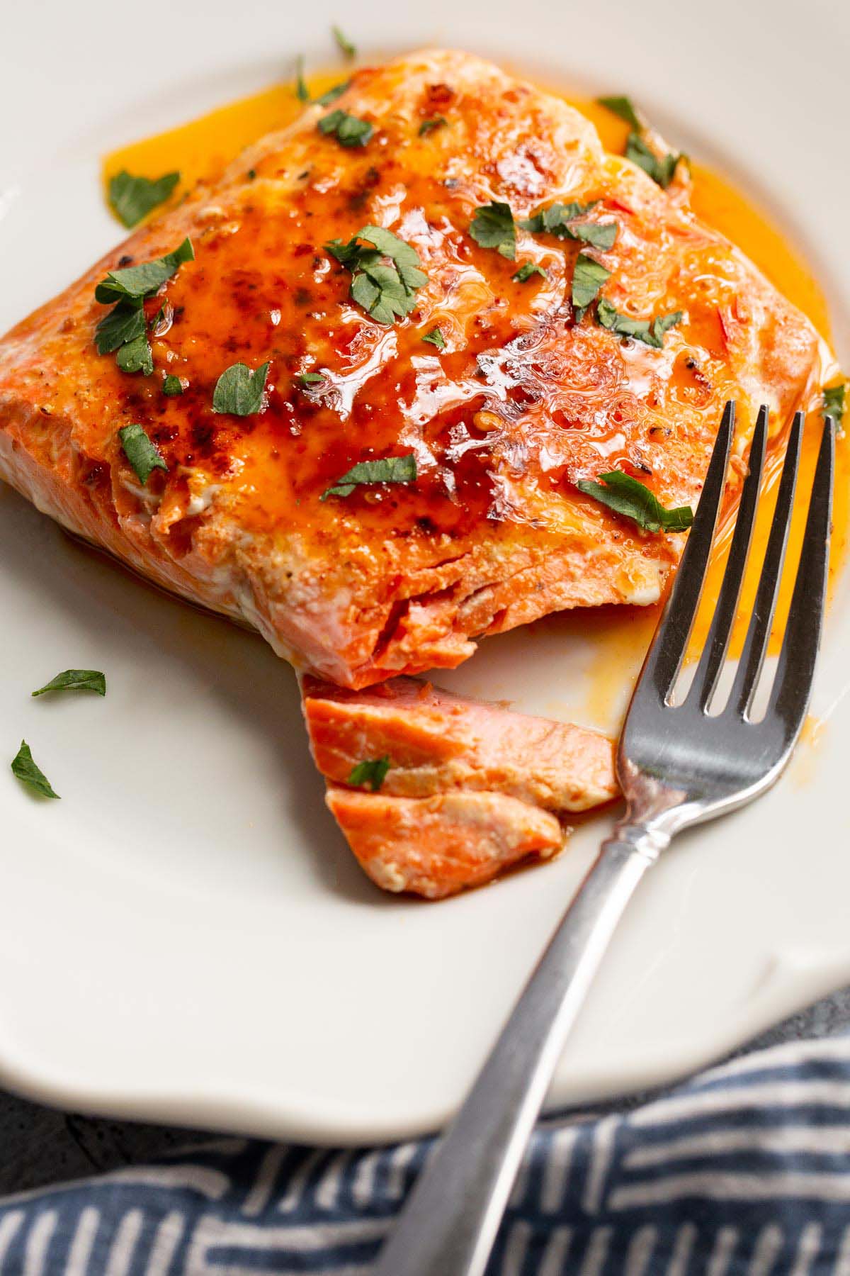 Peri Peri Salmon on a white plate with parsley on top.