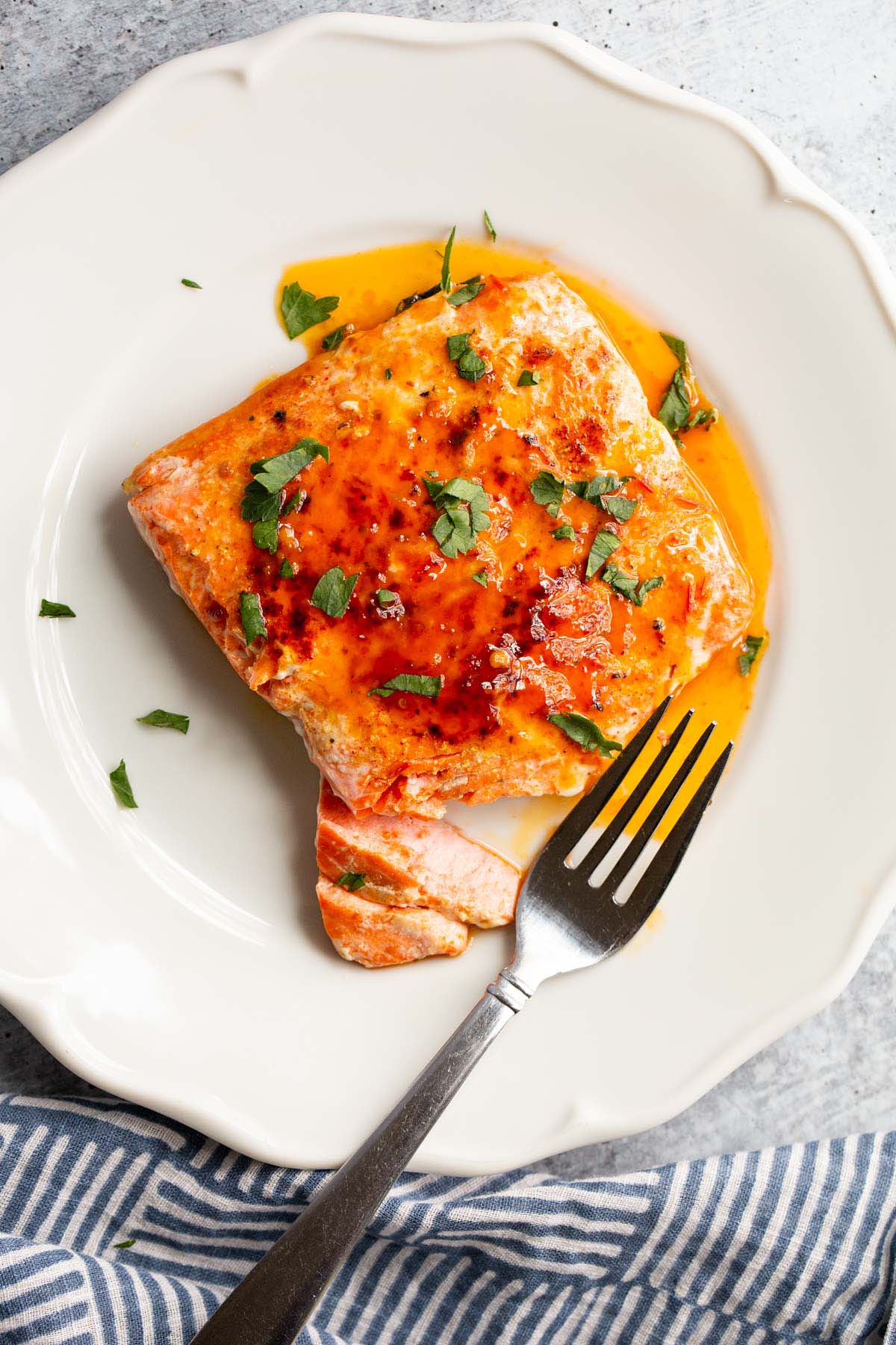 Peri Peri Salmon on a white plate with parsley on top.