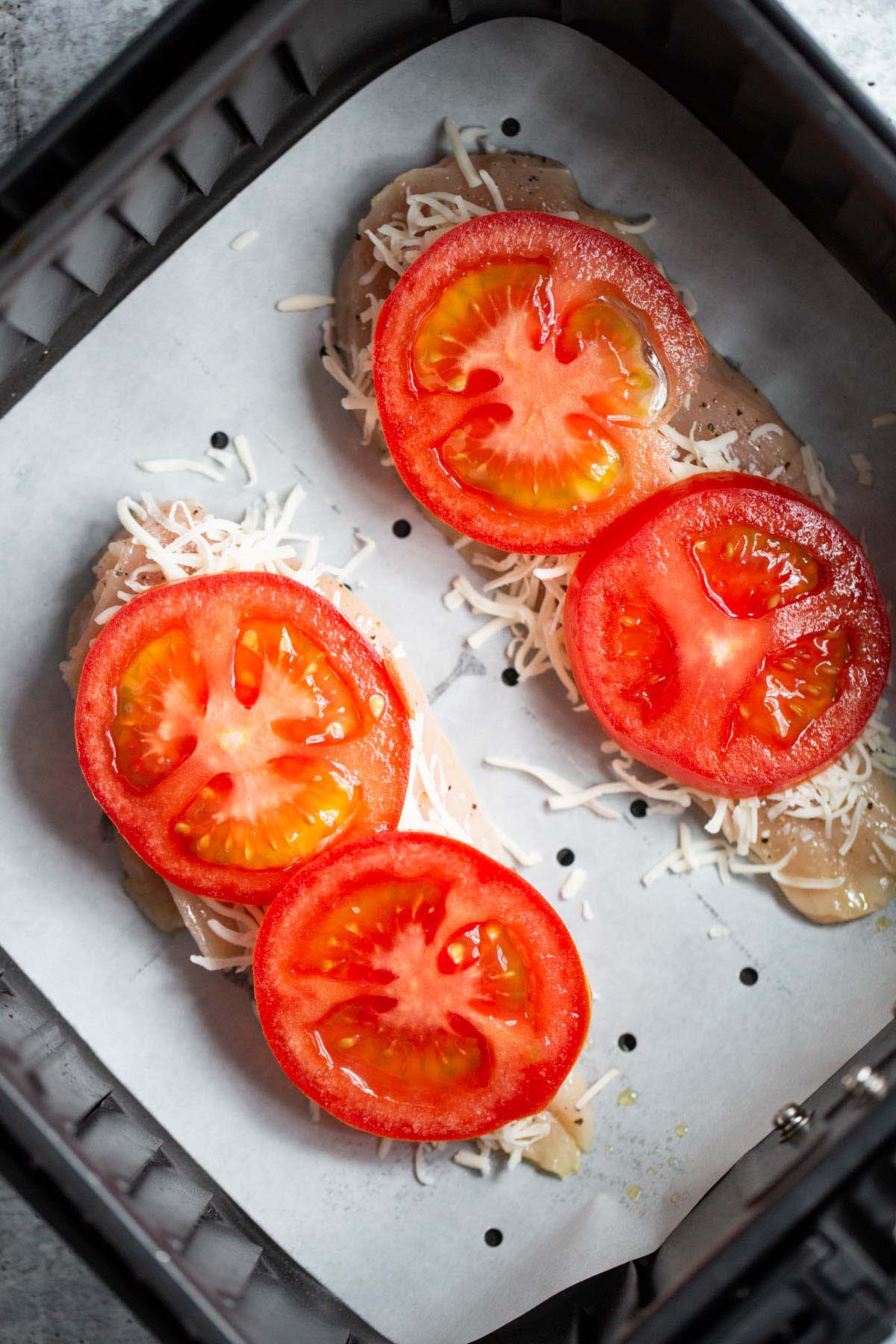 Topping chicken with tomato slices.