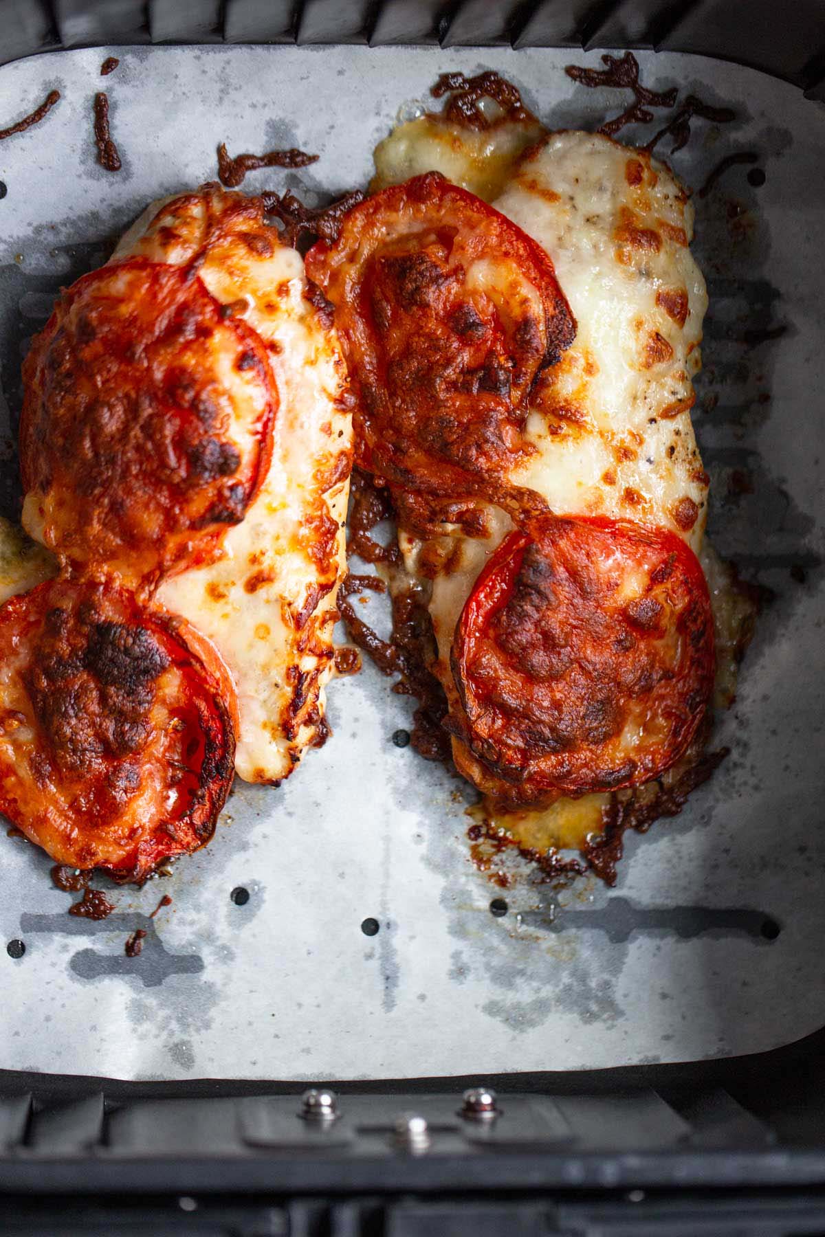 Air fryer caprese chicken in air fryer basket.