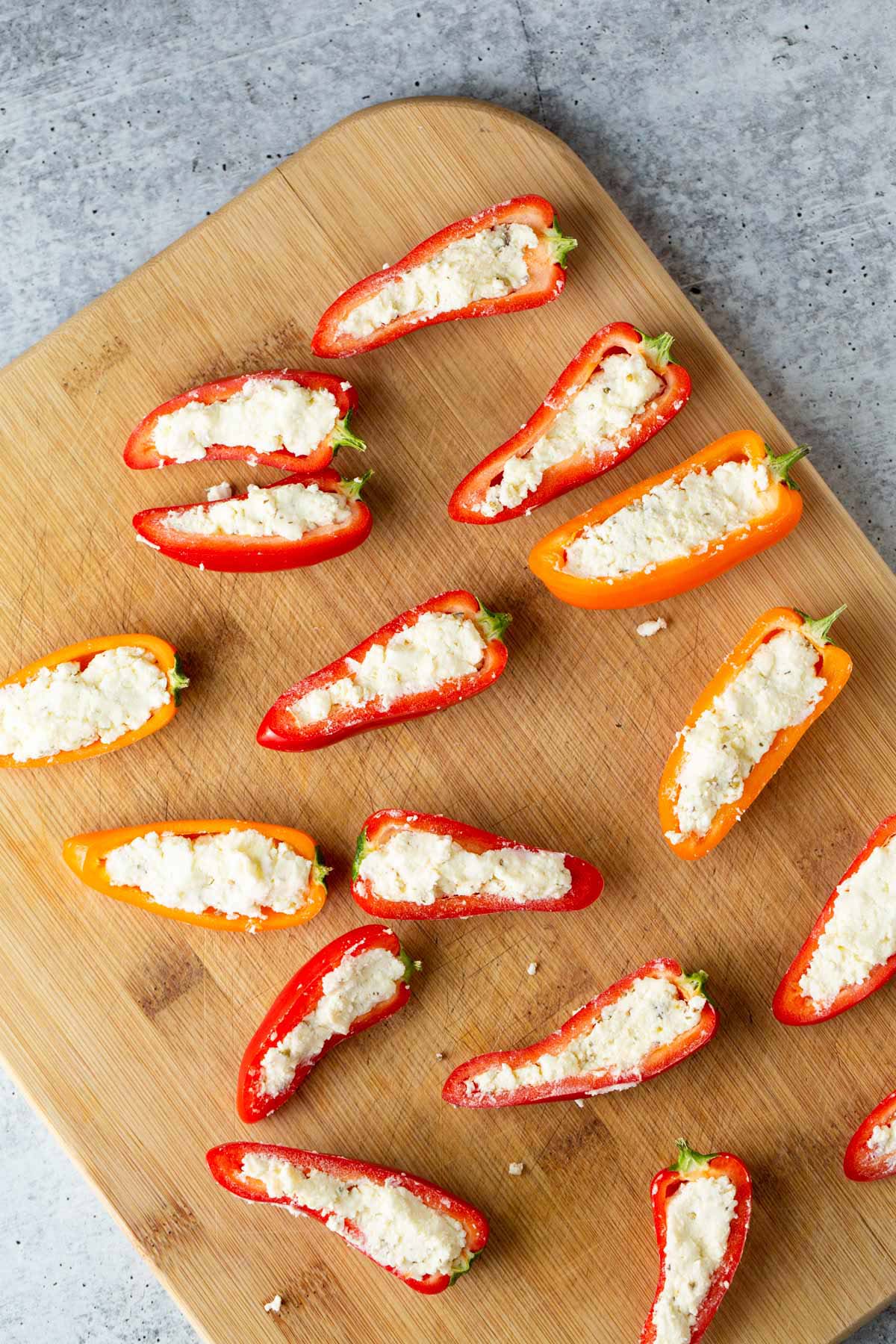 Uncooked feta stuffed mini peppers on cutting board.