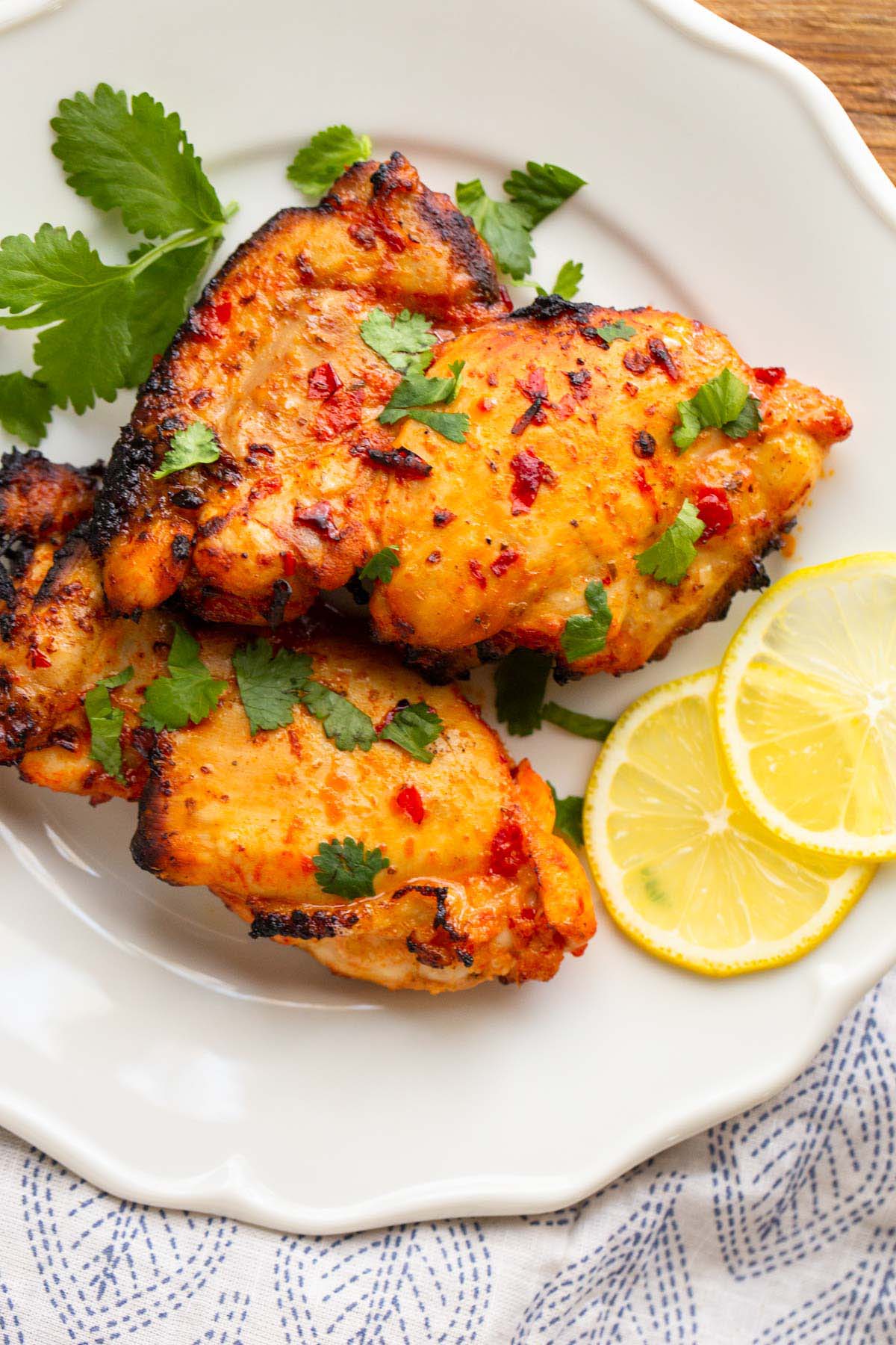 Harissa chicken on a plate with lemon slices.