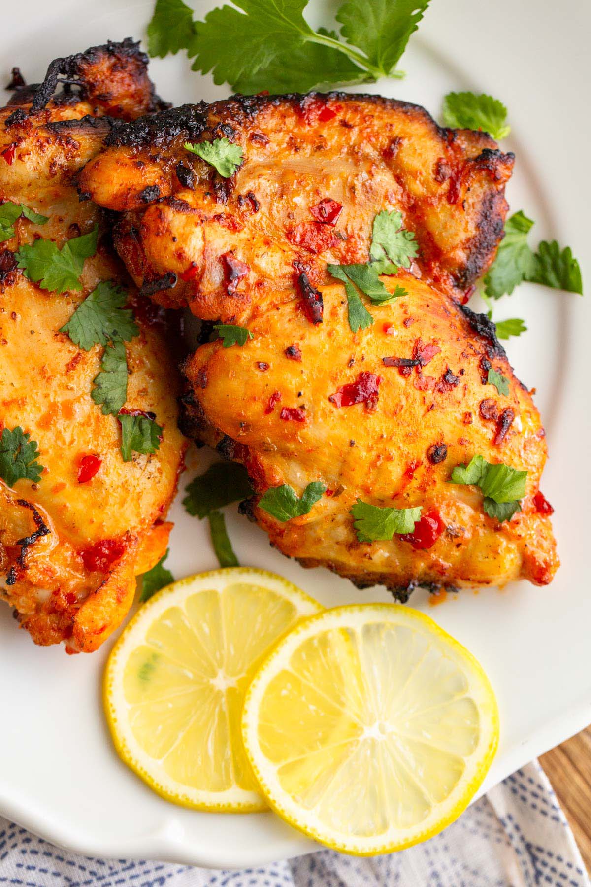 Harissa chicken on a plate with lemon slices.