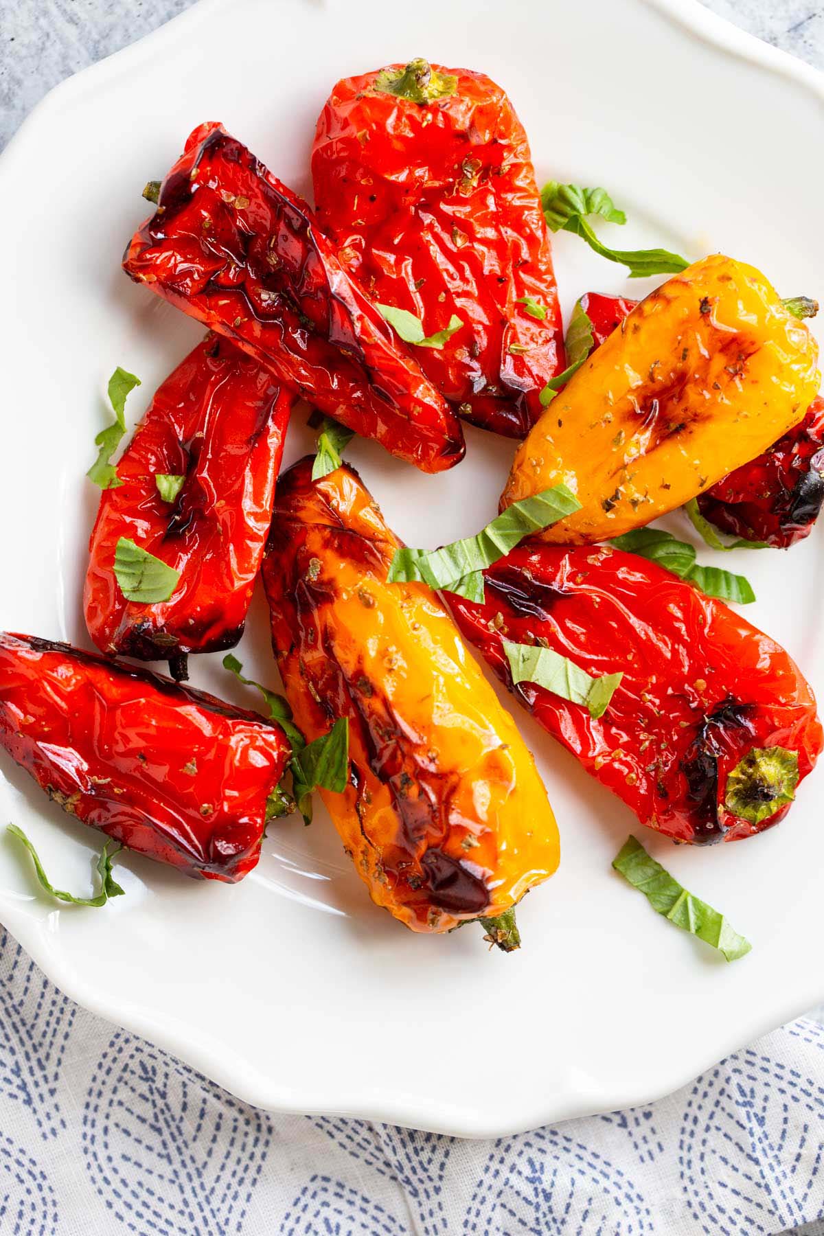 Air fried mini peppers on a plate topped with fresh basil.