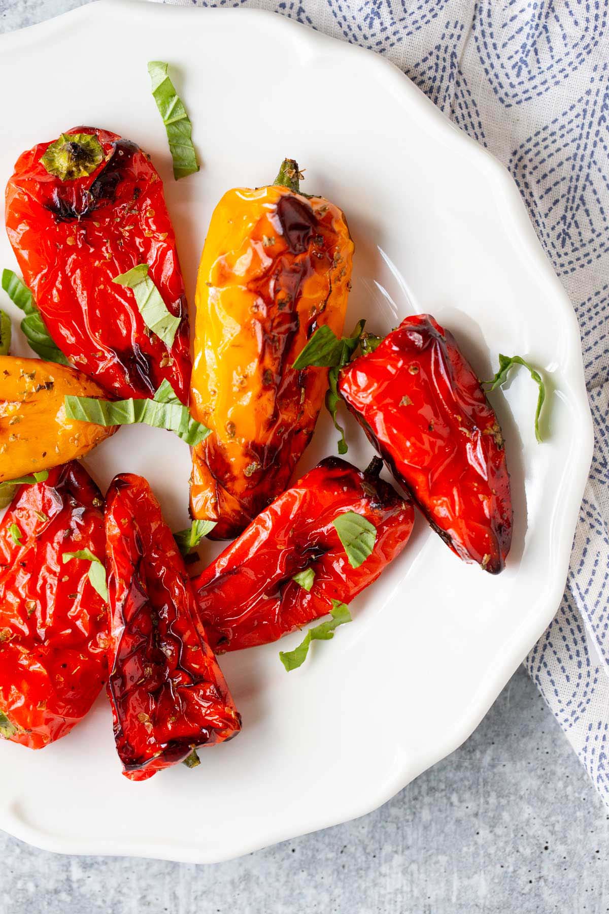 Air fried mini peppers on a plate topped with fresh basil.