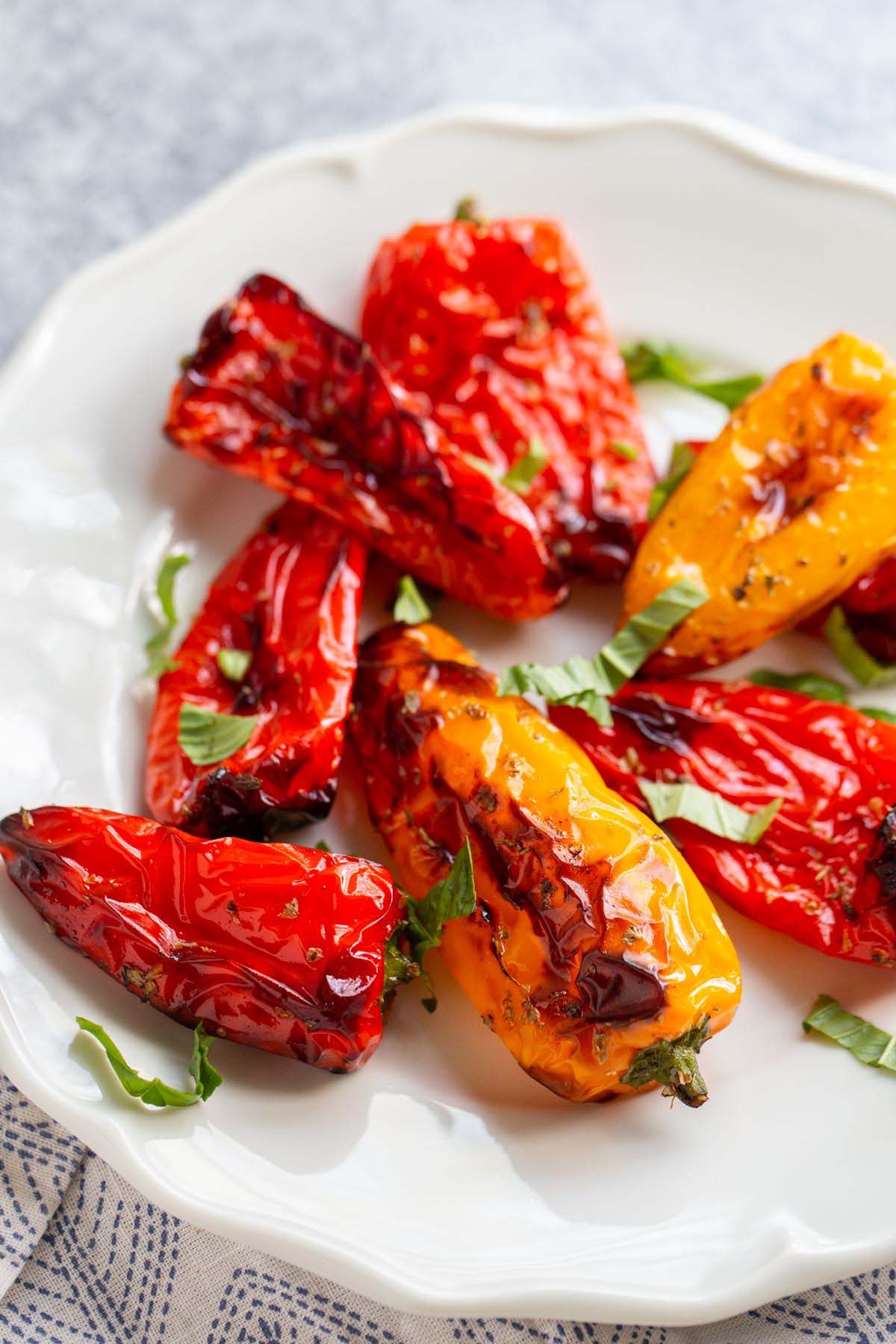 Air fried mini peppers on a plate topped with fresh basil.