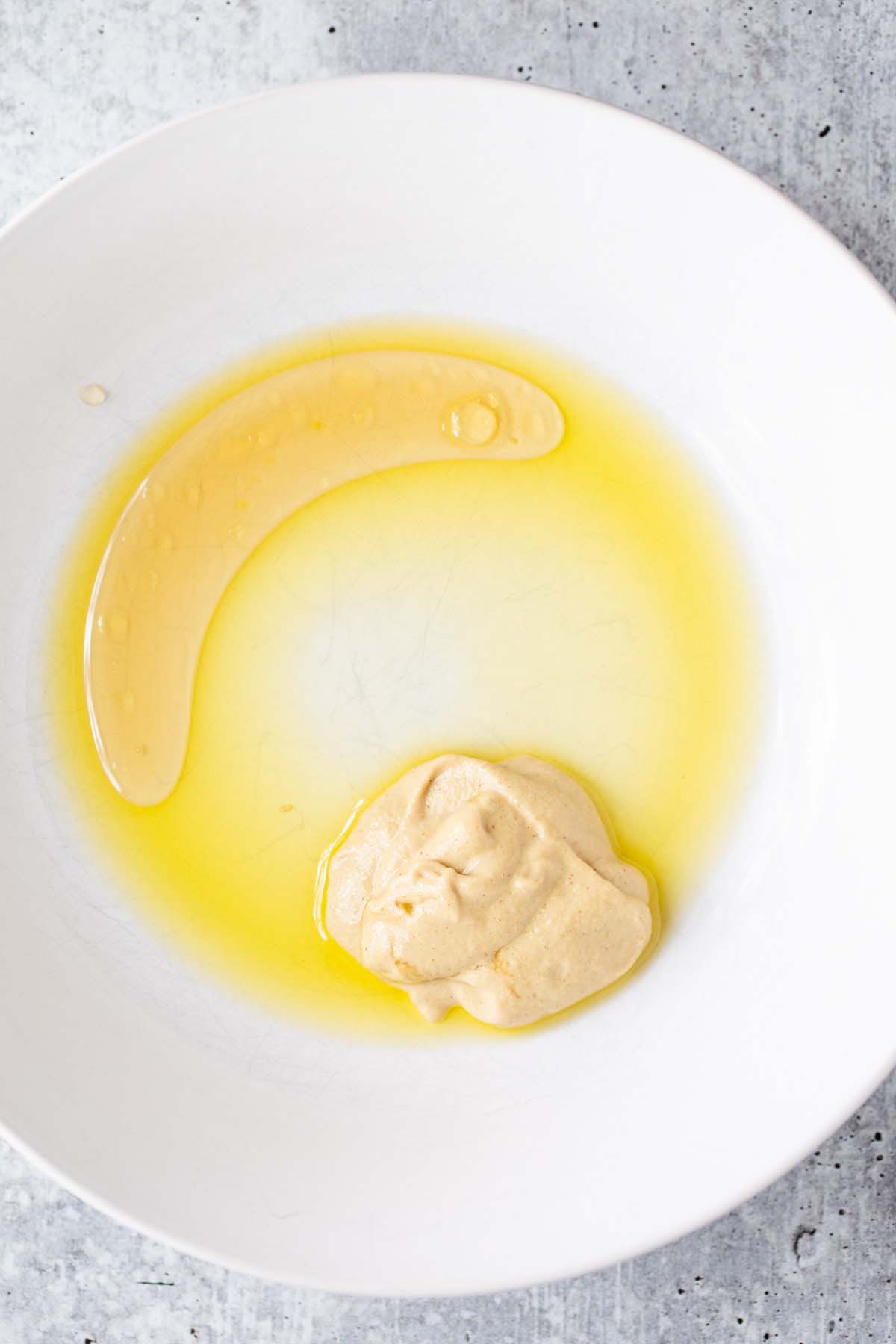 Olive oil, honey, and dijon in a bowl.