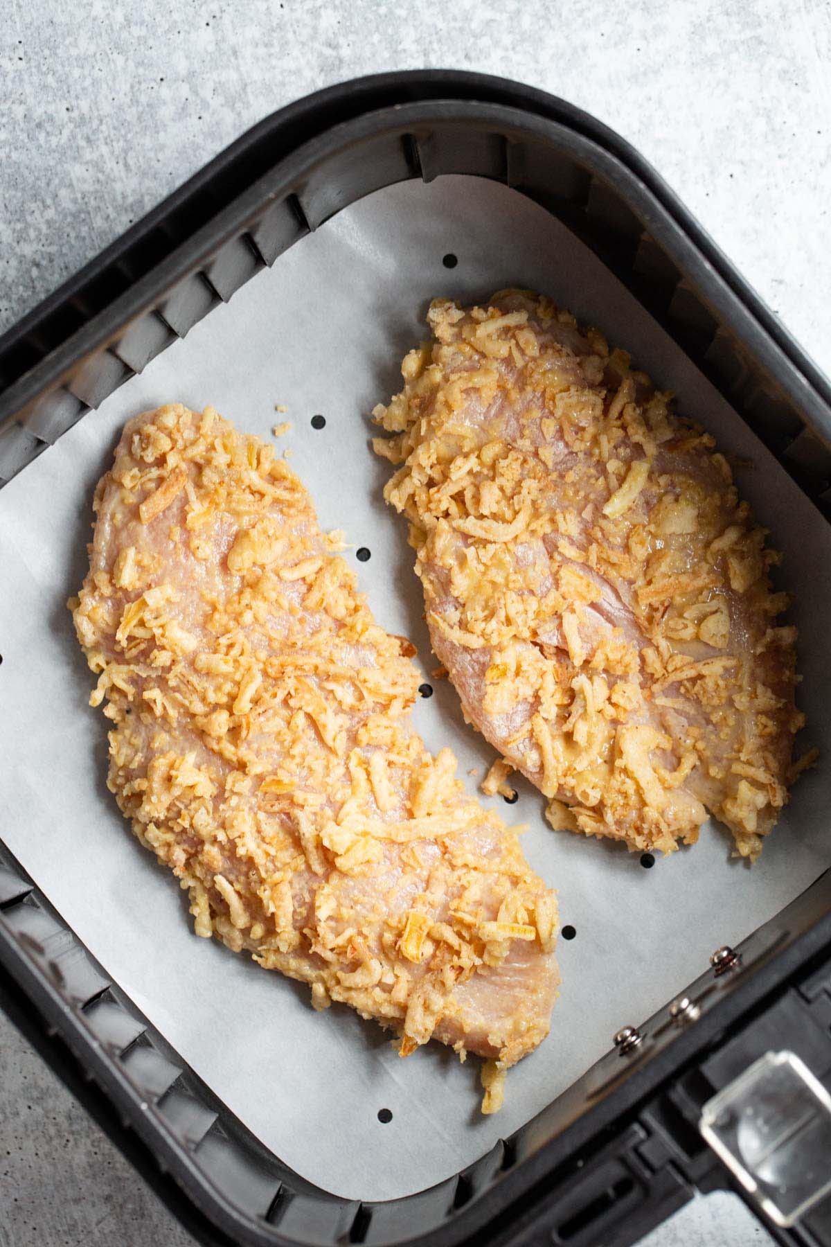 Uncooked air fryer crunchy onion chicken in air fryer basket.