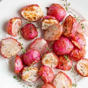 Air fryer radishes on a plate with thyme leaves.