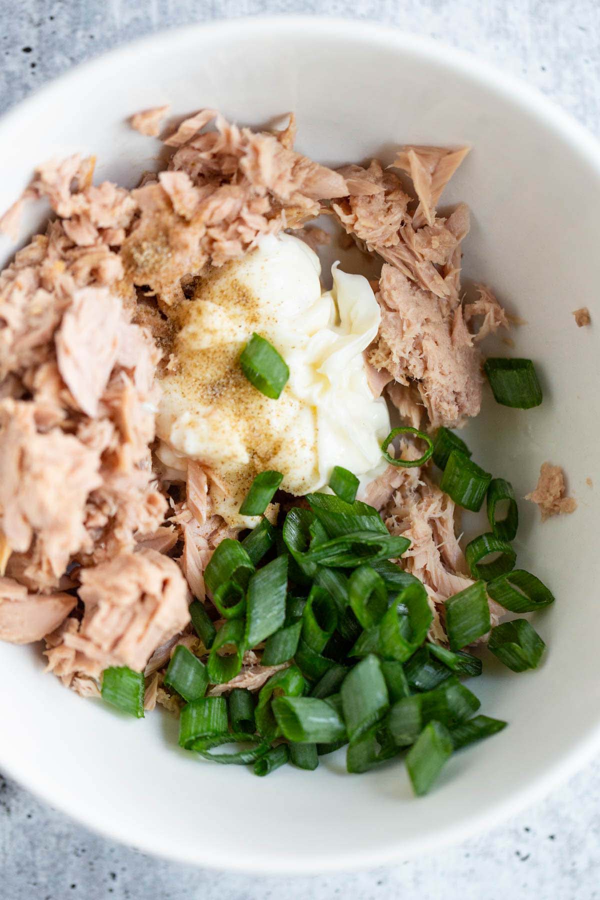 Mixing together tuna, mayo, and green onions.