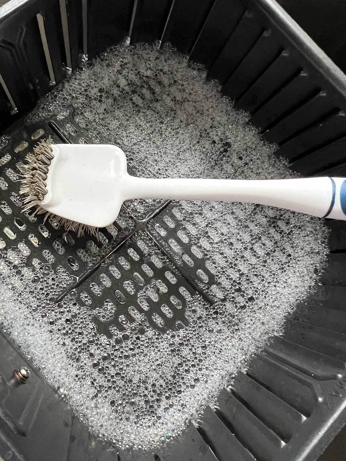 Scrubbing air fryer basket clean.