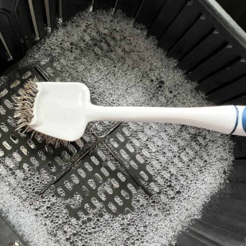 Scrubbing air fryer basket clean.