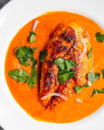 Spicy paprika chicken in a tomato butter sauce topped with red onions and parsley.