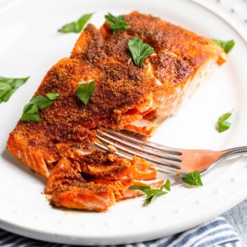 Blackened salmon on a plate flaked with a fork.